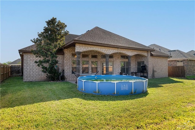 back of house featuring a lawn and a fenced in pool