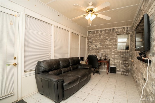 living room with ceiling fan, light tile patterned floors, ornamental molding, and brick wall