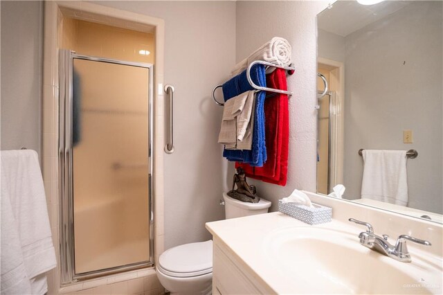 bathroom featuring a shower with door, vanity, and toilet