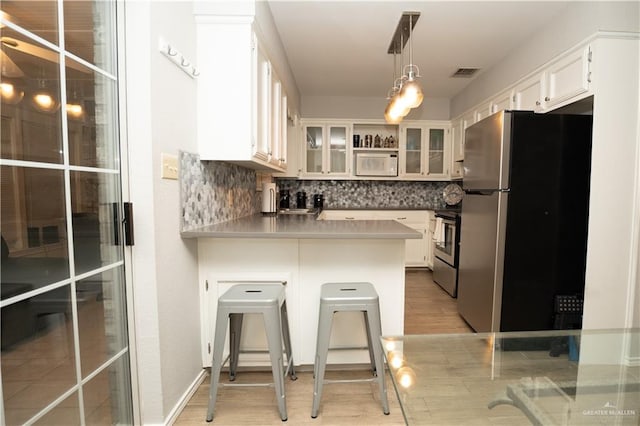 kitchen featuring backsplash, stainless steel appliances, white cabinetry, and light hardwood / wood-style flooring