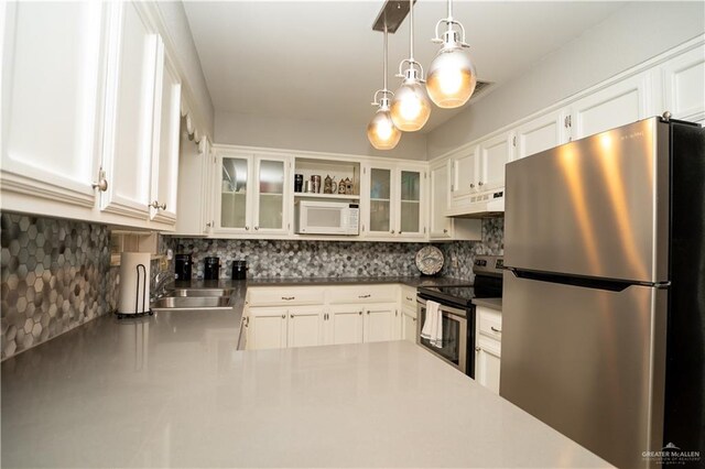 kitchen featuring pendant lighting, backsplash, premium range hood, sink, and stainless steel appliances