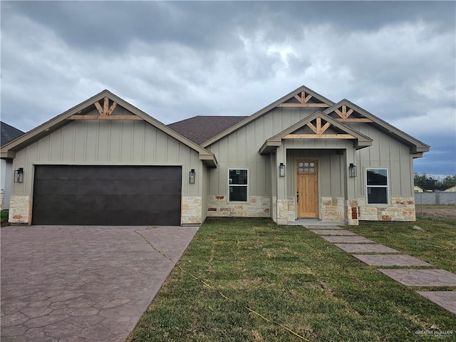 view of front of property with a front yard, stone siding, driveway, and an attached garage