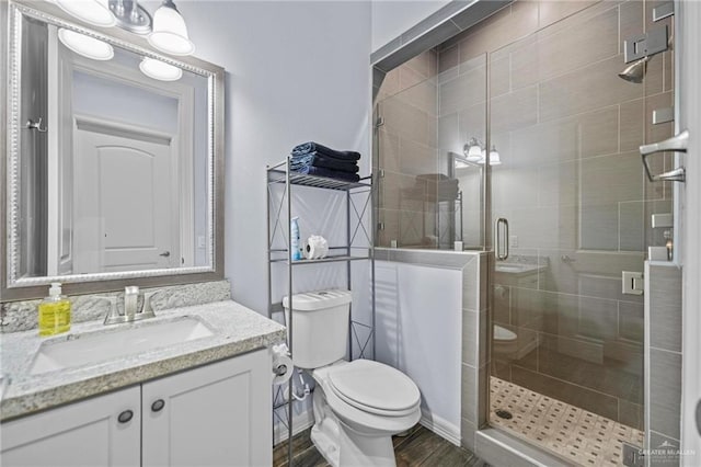 bathroom featuring vanity, hardwood / wood-style flooring, toilet, and a shower with shower door