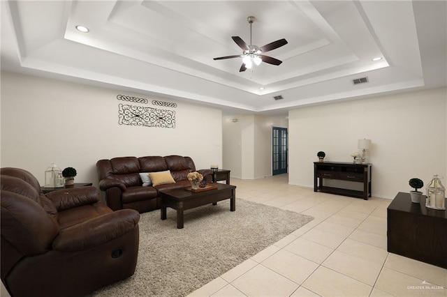 living room featuring ceiling fan, a raised ceiling, and light tile patterned floors