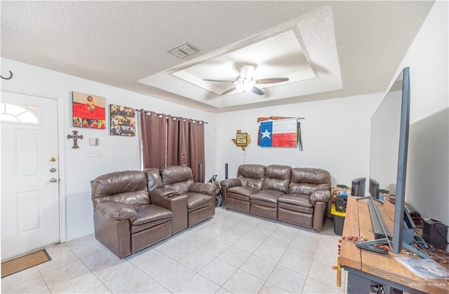 living room with a textured ceiling, a tray ceiling, and ceiling fan