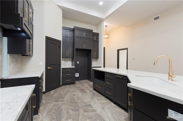 1209 Rhett Dr, Pharr, TX 78577 - kitchen with a sink, light stone counters, range hood, backsplash, and a chandelier