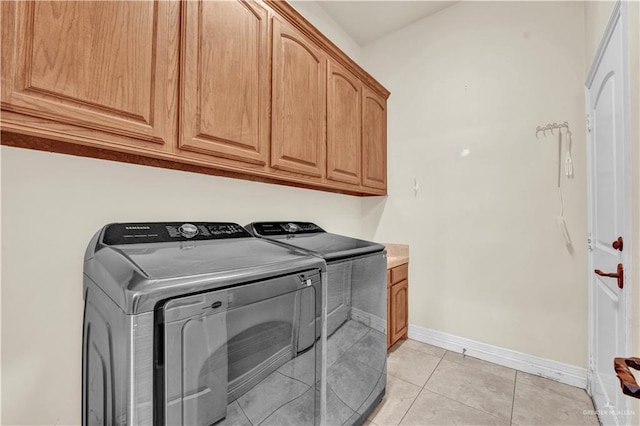 washroom with cabinet space, independent washer and dryer, baseboards, and light tile patterned floors