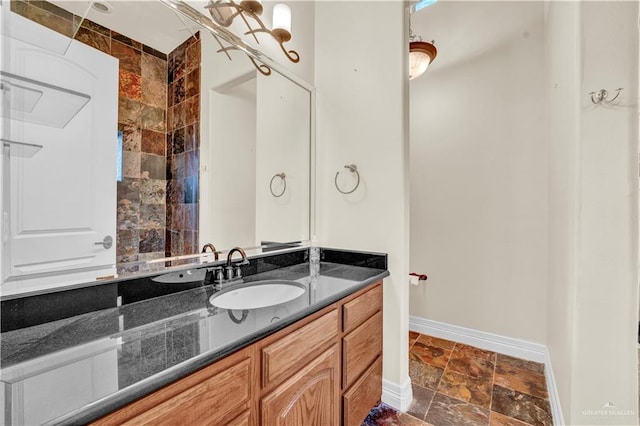 full bathroom with baseboards, stone tile flooring, and vanity