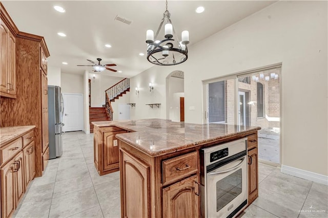 kitchen with visible vents, arched walkways, a kitchen island, appliances with stainless steel finishes, and hanging light fixtures