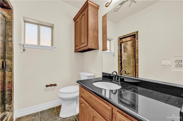 bathroom with toilet, vanity, baseboards, stone finish flooring, and a stall shower