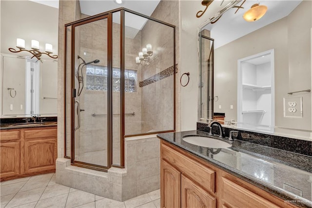 full bath featuring a stall shower, tile patterned flooring, two vanities, and a sink