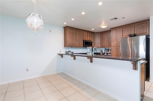 310 E Houston St Unit 1403, Port Isabel, TX 78578 - kitchen featuring stainless steel microwave, a breakfast bar, a peninsula, recessed lighting, and brown cabinets