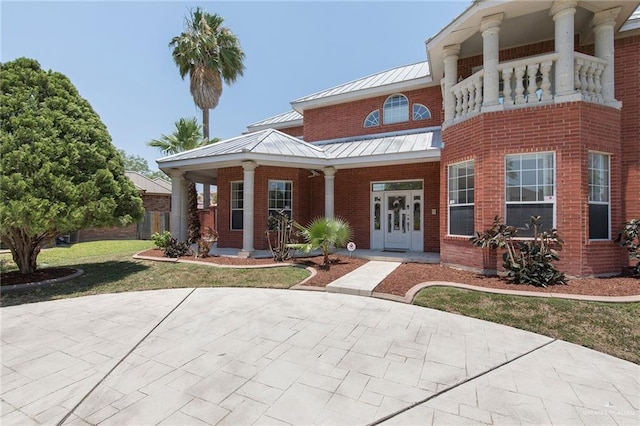 3305 W San Luis Cir, Mission, TX 78573 - view of front of property with a standing seam roof, covered porch, a front lawn, brick siding, and a balcony