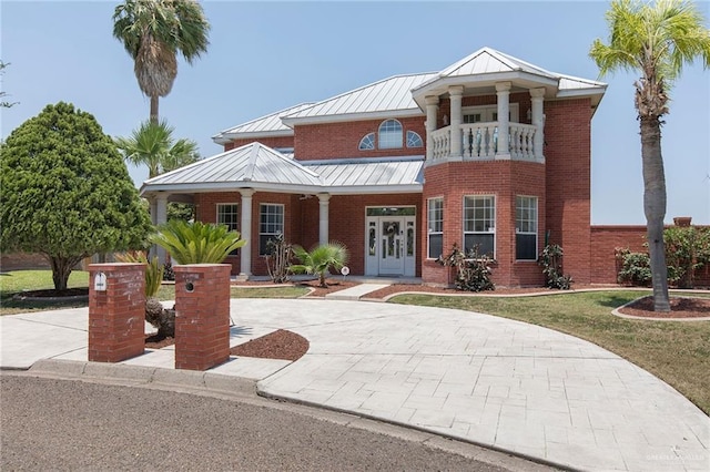 3305 W San Luis Cir, Mission, TX 78573 - neoclassical home featuring a standing seam roof, a porch, a balcony, metal roof, and brick siding