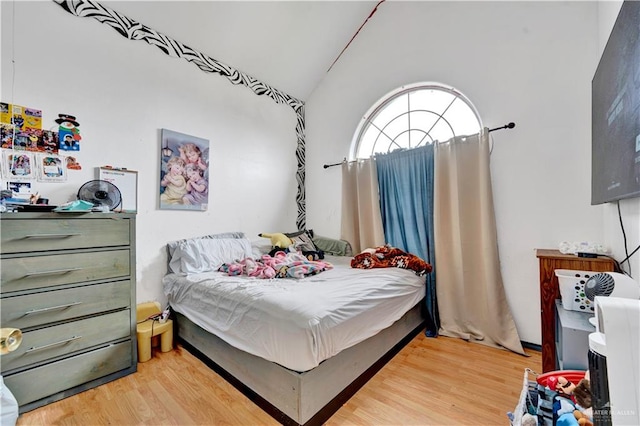 bedroom with vaulted ceiling and light wood-style floors