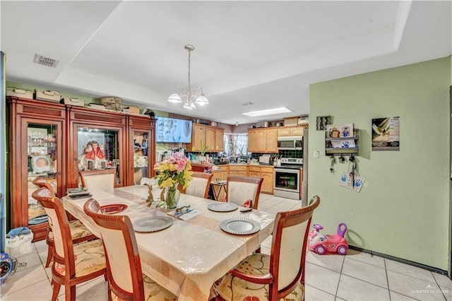 dining area featuring a raised ceiling, visible vents, an inviting chandelier, and light tile patterned floors