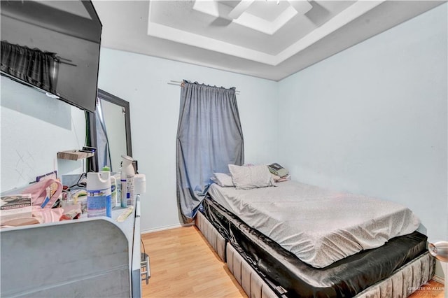 bedroom with light wood-type flooring and a raised ceiling