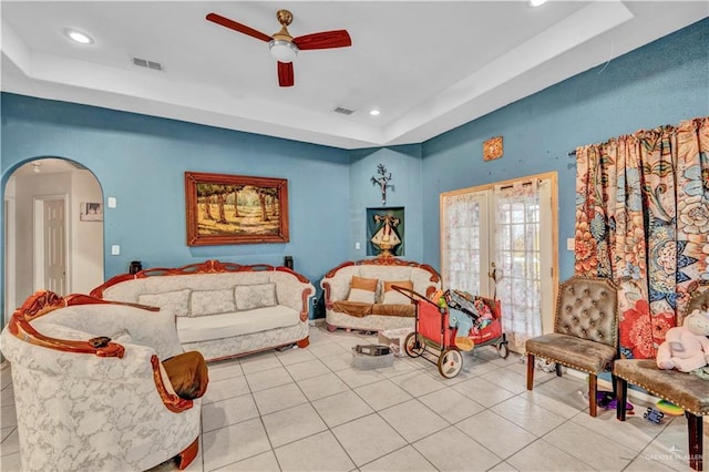 living area with light tile patterned floors, visible vents, arched walkways, a raised ceiling, and french doors