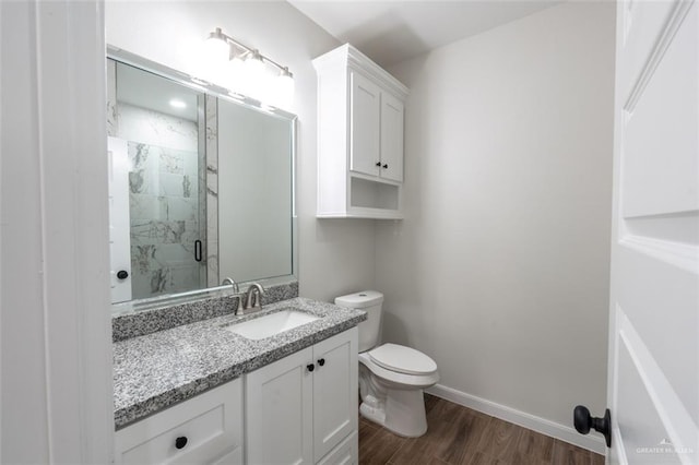 bathroom with hardwood / wood-style floors, vanity, toilet, and a shower with shower door