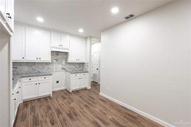 kitchen featuring backsplash, white cabinetry, light stone counters, and dark hardwood / wood-style floors