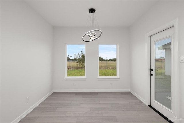 unfurnished dining area featuring light hardwood / wood-style flooring and a notable chandelier