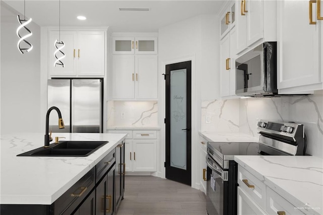 kitchen featuring stainless steel appliances, hanging light fixtures, light stone countertops, white cabinets, and sink