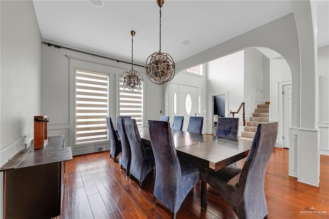 1900 E 2 Mile Line Rd, Mission, TX 78574 - dining space with dark wood-style flooring, a notable chandelier, a decorative wall, arched walkways, and stairs