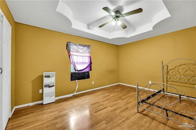 bedroom with a raised ceiling, ceiling fan, and hardwood / wood-style flooring