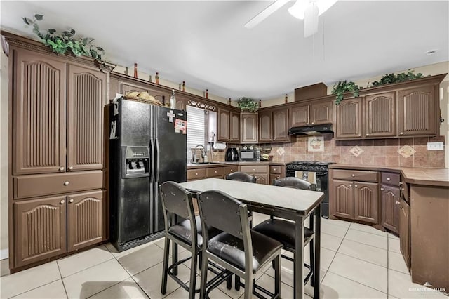 kitchen featuring black appliances, sink, ceiling fan, dark brown cabinets, and light tile patterned flooring