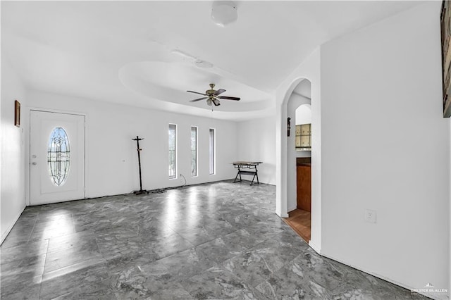 foyer entrance with a tray ceiling and ceiling fan