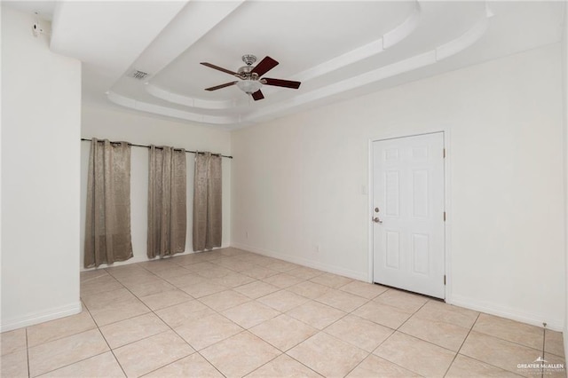 unfurnished room featuring light tile patterned floors, a raised ceiling, and ceiling fan