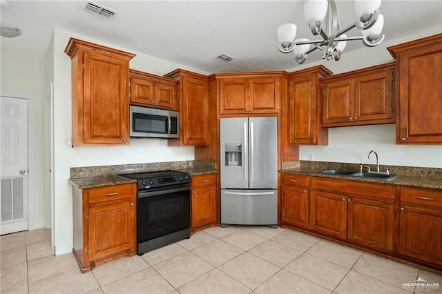 kitchen with sink, light tile patterned floors, appliances with stainless steel finishes, a notable chandelier, and dark stone counters