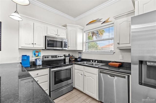 102 E Gardenia St, South Padre Island, TX 78597 - kitchen with white cabinets, a sink, appliances with stainless steel finishes, ornamental molding, and hanging light fixtures