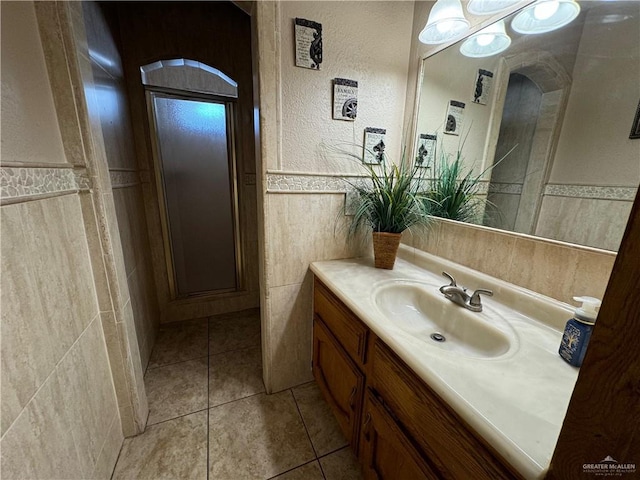 bathroom with tile patterned flooring, vanity, tile walls, and walk in shower