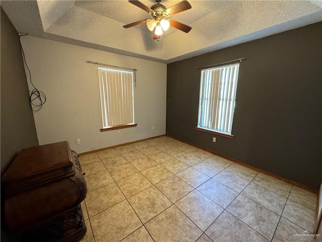 spare room featuring ceiling fan, light tile patterned flooring, and a textured ceiling