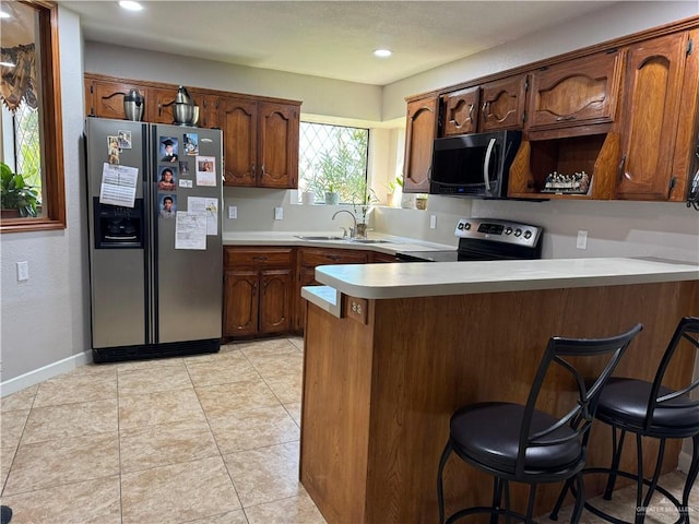 kitchen with a breakfast bar area, kitchen peninsula, sink, and appliances with stainless steel finishes