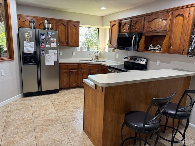 kitchen with kitchen peninsula, a breakfast bar, stainless steel appliances, sink, and light tile patterned flooring