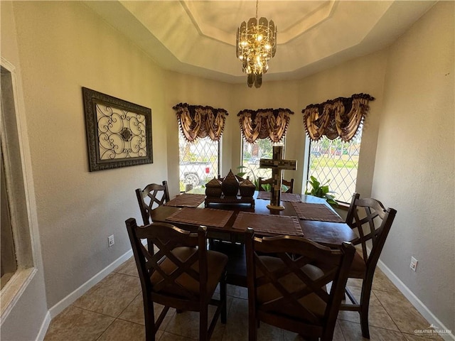 tiled dining room featuring an inviting chandelier, a raised ceiling, and plenty of natural light