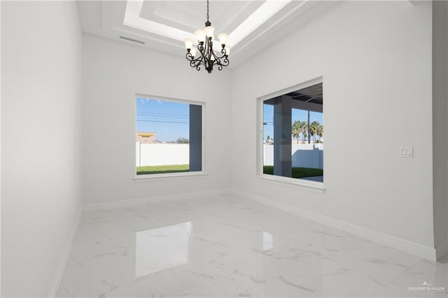 unfurnished room featuring marble finish floor, a raised ceiling, baseboards, a notable chandelier, and visible vents