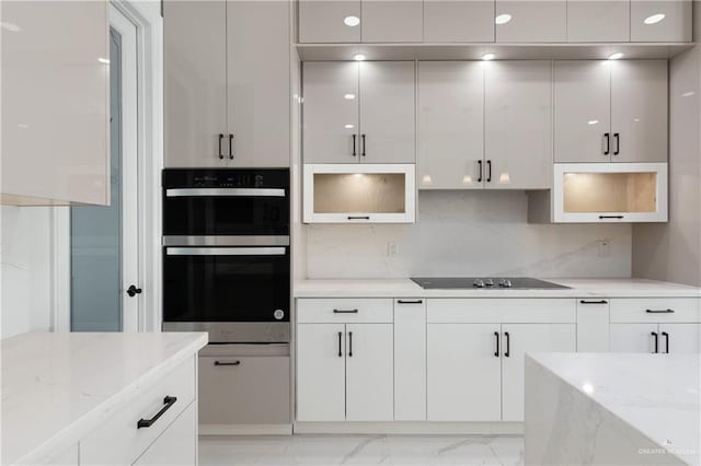 kitchen featuring white cabinets, black electric stovetop, marble finish floor, and double oven