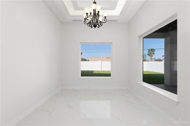 empty room with a tray ceiling, visible vents, marble finish floor, and an inviting chandelier