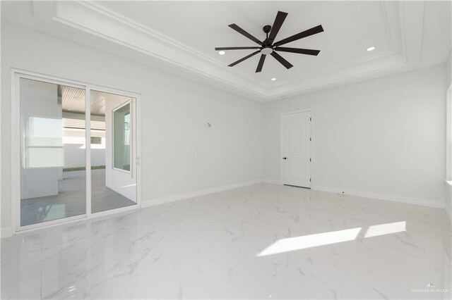 unfurnished room with baseboards, a tray ceiling, marble finish floor, and crown molding