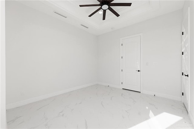 empty room with ceiling fan, marble finish floor, visible vents, and a raised ceiling