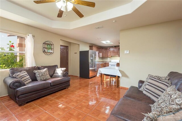 tiled living room featuring a tray ceiling and ceiling fan