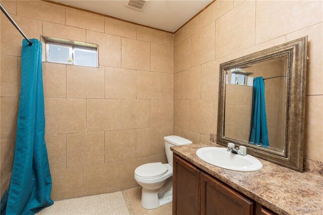 bathroom with tile patterned flooring, vanity, toilet, and tile walls