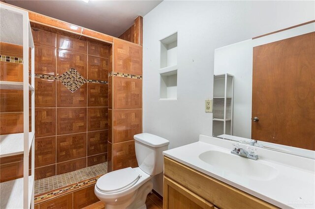 bathroom with tiled shower, vanity, and toilet