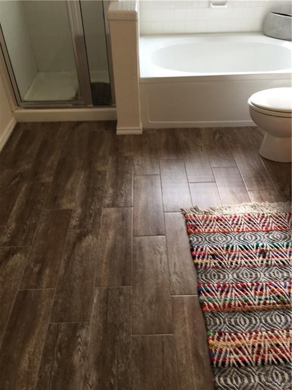 bathroom featuring wood-type flooring, shower with separate bathtub, and toilet