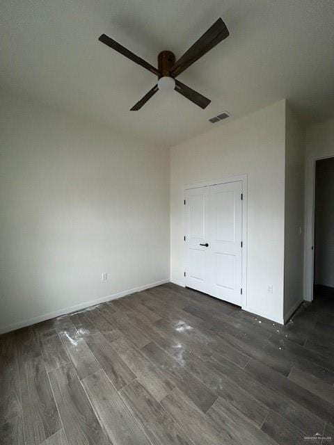 unfurnished bedroom with dark wood-type flooring, a closet, and ceiling fan