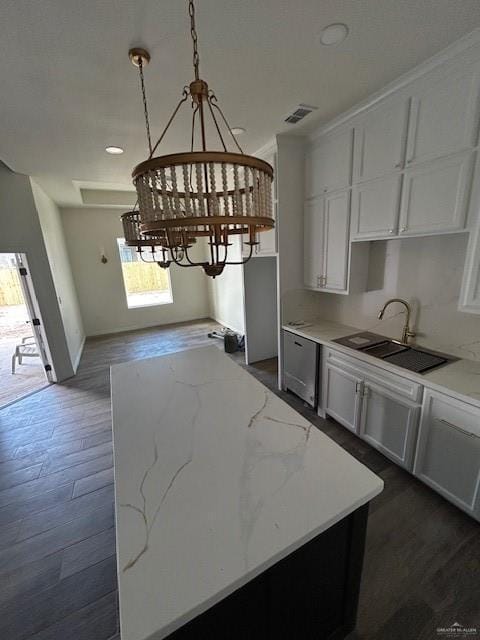 kitchen featuring light stone countertops, sink, white cabinets, and decorative light fixtures