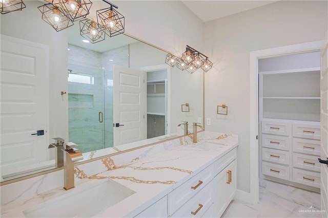 full bathroom featuring marble finish floor, a marble finish shower, double vanity, a spacious closet, and a sink